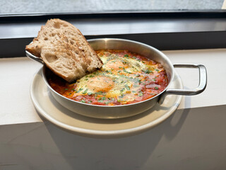 Spicy Shakshuka with Eggs, Peppers, Tomatoes, and Cilantro in a Steel Skillet, Served with Bread. Healthy Authentic Food Concept. Handmade Mobile Photo, Selective Focus, Not AI