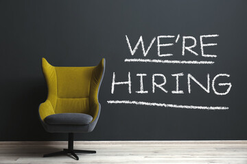 We Are Hiring. Empty office chair near dark wall. Recruitment, human resources concept