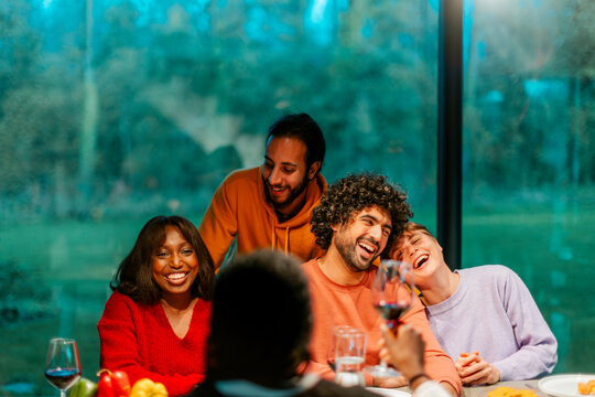 Happy friends laughing and raising a toast during a dinner party