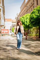 Fototapeta premium Full length of a blond haired woman wlaking on the city street