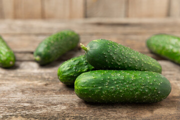 Cucumber on wooden background. Slice of cucumber on background. Fresh organic green cucumbers gherkin. Vegan. Salad ingredient. Farm vegetables. Cut vegetables with knife. Space for text. Copy space