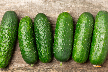 Cucumber on wooden background. Slice of cucumber on background. Fresh organic green cucumbers gherkin. Vegan. Salad ingredient. Farm vegetables. Cut vegetables with knife. Space for text. Copy space