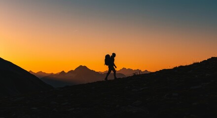 Silhouette of hiker with backpack enjoying sunrise in the mountains