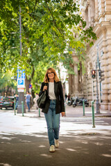Naklejka premium Blond haired woman walking on the city street on an autumn day