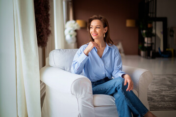 Obraz premium Brunette haired woman relaxing at home in her comfortable armchair