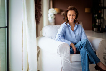 Obraz premium Brunette haired woman relaxing at home in her comfortable armchair