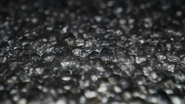 Macro Close-Up of Shimmering Black Textured Surface with Abstract Metallic Patterns in Low Light