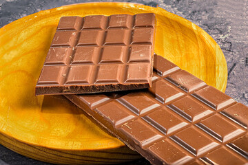 Milk chocolate bars on wooden plate