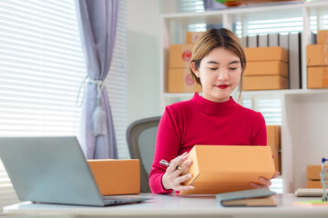 businesswoman in red shirt standing holding parcel box ready to deliver to customer who ordered...