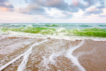 nature background with sea tide in evening light. water surface motion at storm. wave splash with foam on the beach. summer outdoor weather with wind. beautiful view of travel wallpaper with horizon