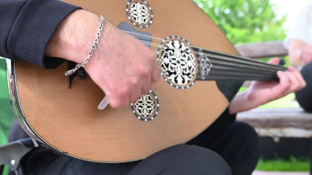 Man playing oud, a traditional musical instrument in Turkey, close-up.