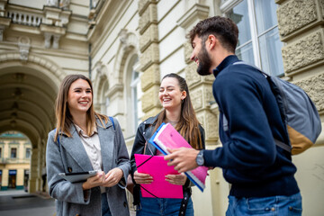 Three Students Holding Books Laughing and Talking Together Outdoors