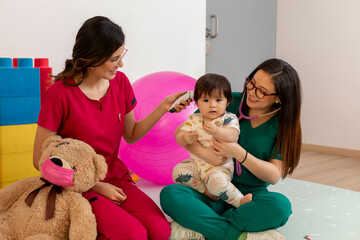 Pediatricians taking temperature of baby girl in doctor's office