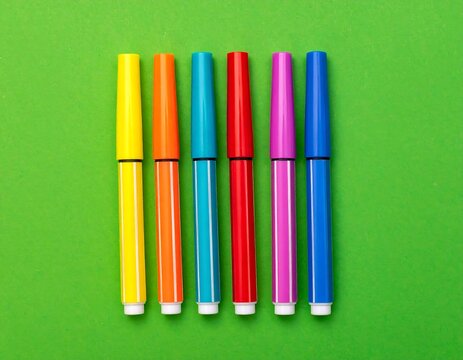 Colorful markers aligned on bright green background, vibrant, top-down view