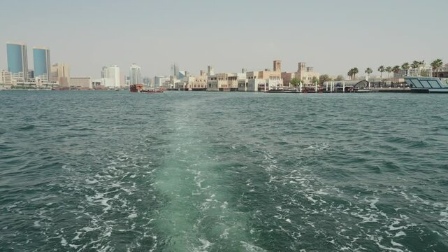 Traditional Arabian wooden boats ship leaving a trail behind UAE