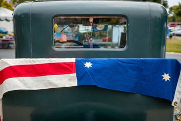 US flag draped over the trunk of a classic car