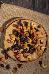 Mixed nuts on wooden background. Nuts, raisins, candied fruits and cones. Vertical