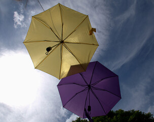 Blue, yellow, purple umbrella suspended, hanged in the sky creates a minimalist artistic scene....