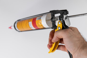 Hand holding caulking gun ready for application of sealant in home improvement project