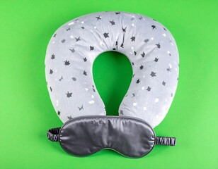 Gray star neck pillow & mask sit on bright green background; travel, relax, comfort