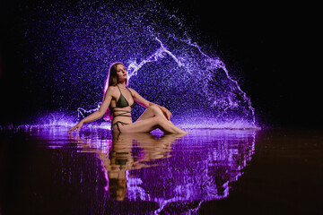 Slender girl posing at the background of purple colored water droplets