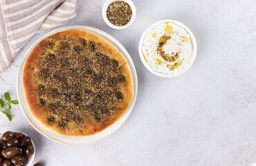 Zaatar Manakish with labneh and olives on gray background. Top view. Copy space.
