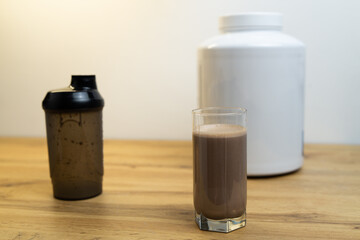 Protein shake in a glass and whey protein powder in a measuring scoop