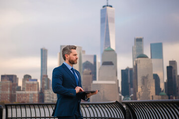 Businessman with laptop in New York City. Financial Manhattan. Office worker hold laptop against cityscape in NYC. Business man in suit using laptop outdoor. Office work on laptop. Hispanic manager.