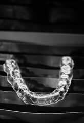 A transparent dental mouthguard lies on neatly folded bags with the same mouthguards.