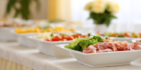 Food is displayed on plates on a table; the dishes include vegetables and meats. The concept is a buffet or meal spread