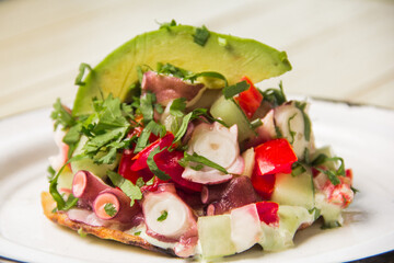 This visually appealing dish features a tostada topped with colorful octopus salad, fresh...