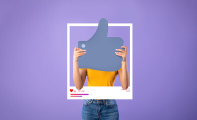 A person is holding a large thumbs up symbol in front of a bright purple background. They wear a...