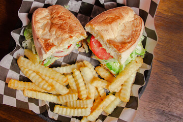 A hearty milanesa mexican torta is presented with fresh vegetables and crispy fries, capturing the essence of comfort food served on a classic checkered plate.