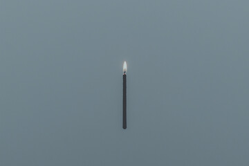 Naklejka premium A lone candle burning brightly against a muted background, symbolizing light and hope