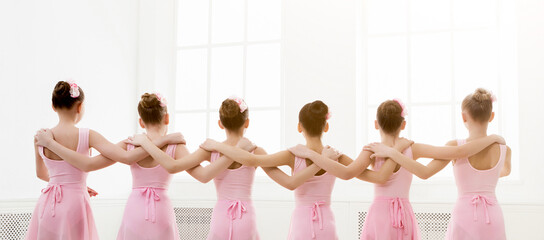Young girls dancing ballet in studio. Choreographed dance by a group of graceful pretty young ballerinas practicing during class before performance. Classical dance school © Prostock-studio