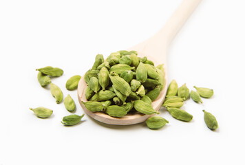 Cardamom seasoning in a wooden spoon close-up at the white background