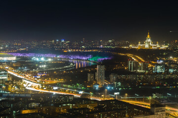 A breathtaking panorama of Moscow at night highlights the city's illuminated skyline. Vibrant colors reflect on the river, while buildings and streets radiate life and energy.
