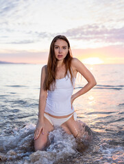 Attractive woman posing in the surf at sunset