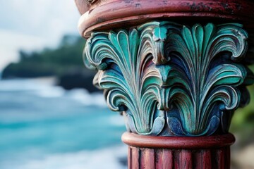 Ornate teal and red column detail against a blurred ocean backdrop.