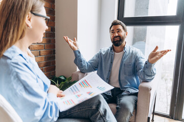 Businessman explaining marketing strategy showing charts to female colleague during a meeting