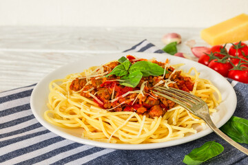 Spaghetti Bolognese with beef meat sauce, basil and grated parmesan cheese on white plate with fork on napkin over white wooden background. Italian pasta. Tasty food