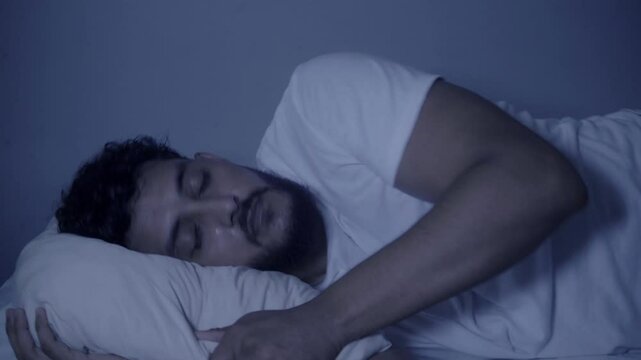 Young man tossing and turning in bed, having trouble sleeping