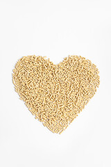 Beige granules in the shape of heart on white background. Vertical. Filler for cat litter box, fuel pellets or food for birds or goats