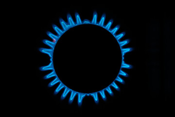 Blue gas flame on a black background. Circular gas burner with blue fire ring.