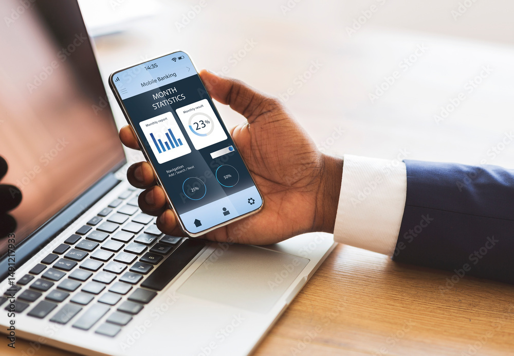 Poster african american businessman hand holding mobile phone with trading app over laptop, creative image.