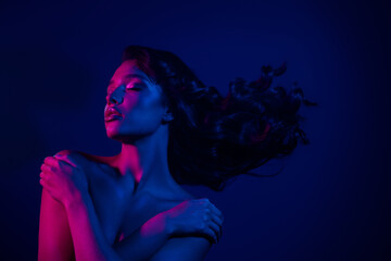 Portrait of a passionate woman in vibrant pink and blue neon lighting, expressing elegance and...