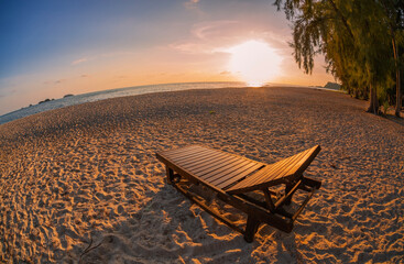 Sunset on an empty tropical beach with a lonely sunbed. Fish eye look