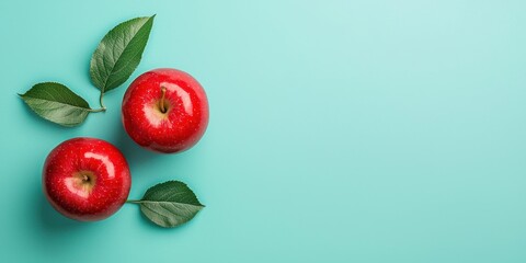 National apple day with red fruit idea. Fresh red apples with green leaves on a turquoise background.