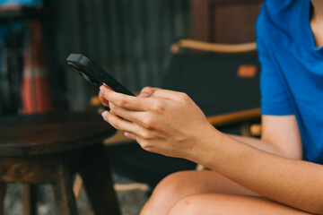 Close-up View of Hands Holding Smartphone with Casual Attire in Relaxed Outdoor Setting