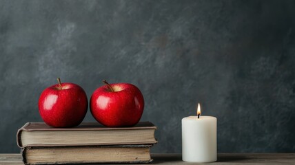 National apple day with red fruit idea. Two red apples on old books beside a candle.